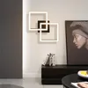A modern living room with a geometric LED wall light, a dark wood cabinet with books, and a large framed portrait. Produktbild-Vorschau