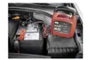 A car battery charger is connected to a car battery in an engine bay. Produktbild-Vorschau