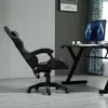 A black ergonomic gaming chair is shown in a room with a desk and computer. Produktbild-Vorschau
