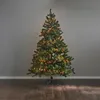 A decorated Christmas tree with warm white LED lights stands on a wooden floor against a gray wall. Podgląd zdjęcia produktu