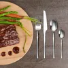 A steak dinner with asparagus and carrots is presented on a wooden plate, accompanied by a set of silverware. Náhled obrázku produktu