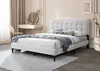 A bedroom scene featuring a white upholstered bed with blue and white striped pillows and a blue throw blanket. Náhľad obrázku produktu