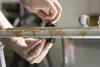 A person's hands are shown holding and using a tool to make a hole in a metal surface. Produktbild-Vorschau