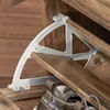 A close-up view of a shoe cabinet with a white bracket holding up a wooden shelf. A brown shoe is visible on the lower shelf. Produktbild-Vorschau
