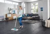 A woman is cleaning a modern living room with a mop. Produktbild-Vorschau