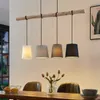 A dining table with chairs and a pendant light fixture hanging above. Produktbild-Vorschau