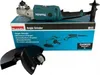 The image shows the packaging of a Makita angle grinder, along with the grinder itself and some accessories. Produktbild-Vorschau