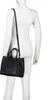 A mannequin wearing a white long-sleeved shirt and a black handbag. Voir les images du produit