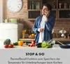 A man is talking on the phone while preparing food in a kitchen. Produktbild-Vorschau