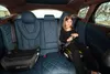 A young girl sits in the back seat of a car, buckled into a car seat. Náhľad obrázku produktu