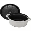 A white cast iron oval casserole dish with its black lid is shown against a white background. The lid is slightly ajar, revealing the inside of the dish. Voir les images du produit