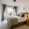 A bedroom with a bed, curtains, and a window overlooking greenery. Podgląd zdjęcia produktu