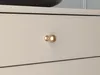 A close-up shot of a gold drawer knob on a light-colored drawer. Náhľad obrázku produktu