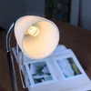 A close-up of a desk lamp illuminating an open book. Anteprima dell’immagine prodotto