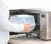 A person is placing a baby bottle sterilizer into a microwave. Náhľad obrázku produktu