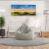 A modern living room with a gray bean bag chair, a sofa, a plant, a floor lamp, and a painting on the wall. Voir les images du produit