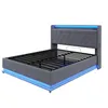 A grey upholstered bed frame with blue LED lighting around the base and headboard, shown from a three-quarter angle against a white background. Voir les images du produit