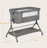 A grey baby bassinet with a metal frame and a storage shelf underneath, shown with dimensions indicated by text overlays. Produktbild-Vorschau