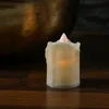 A close-up of a small LED candle on a wooden surface, with a large metallic bowl in the background. Produktbild-Vorschau