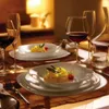 A table setting with plates of pasta, wine glasses, and a carafe. Voir les images du produit