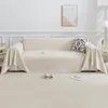 A cream-colored sofa with a throw blanket draped over it, placed in a well-lit living room. Produktbild-Vorschau