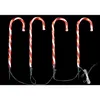 Four illuminated candy cane lawn decorations against a black background. Produktbild-Vorschau