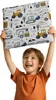 A young boy is holding up a padded wall panel with a construction vehicle print. Náhled obrázku produktu
