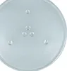 A close-up, top-down view of a round, clear glass microwave turntable plate with three small indentations in the center for a rotating mechanism and three larger indentations around the perimeter for stability. Produktbild-Vorschau