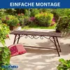 A metal garden bench with decorative scrollwork is placed on a paved patio in a garden setting, with a colorful cushion on the ground next to it. Lush green plants and flowering bushes surround the bench. Anteprima dell’immagine prodotto
