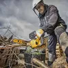 A person is using a DeWALT chainsaw to cut branches in an outdoor setting with a cloudy sky. Voir les images du produit