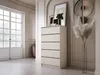 A chest of drawers is placed in a room with a large window and decorative molding. Voir les images du produit