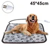 A golden retriever dog lying on a heated pet mat with paw prints on it. The mat is connected to a power cord and plug. Produktbild-Vorschau