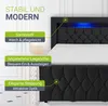 A black upholstered bed frame with blue LED lighting in the headboard, shown from a slightly elevated side angle. Produktbild-Vorschau
