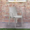 A white rattan chair is placed on a patio in front of a brick wall. Voir les images du produit