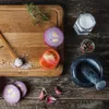 A top-down view of a wooden cutting board with ingredients and a mortar and pestle on a rustic wooden table. Voir les images du produit