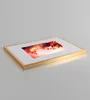 A gold picture frame with a photo of a woman's face adorned with red leaves. Produktbild-Vorschau