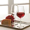 Two wine glasses, one filled with red wine, and a wedge of cheese with grapes on a silver tray. Anteprima dell’immagine prodotto