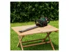 A hedge trimmer rests on a wooden table in a garden setting. Produktbild-Vorschau