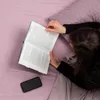 A person reading a book in bed with a phone nearby. Náhľad obrázku produktu