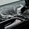 A close-up shot of a car's interior door panel being cleaned with a brush and foam. Náhled obrázku produktu