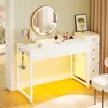 A white vanity table with makeup and accessories, a round mirror with LED lighting, and a stack of drawers next to it. Produktbild-Vorschau