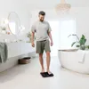 A man stands on a digital scale in a modern bathroom. Produktbild-Vorschau