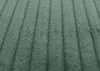 A close-up, textured view of green corduroy fabric with vertical lines. Podgląd zdjęcia produktu