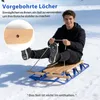 A young man is sitting on a wooden sled in the snow, holding a rope. Náhled obrázku produktu