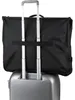 A black garment bag is attached to the handle of a silver rolling suitcase. Anteprima dell’immagine prodotto