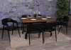 A dining set with chairs around a wooden table, placed on a rug in front of a stone wall. Náhled obrázku produktu