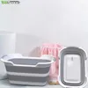 A collapsible basin and a folded basin are displayed on a countertop with a towel in a basket in the background. Voir les images du produit