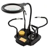 A black soldering helping hand tool with a magnifying glass and LED light, on a white background. Produktbild-Vorschau