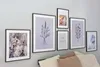 A collection of framed art prints displayed on a wall above a bed. Produktbild-Vorschau