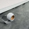 A roll of gray repair tape is shown on a dark gray surface next to a white textured wall. Produktbild-Vorschau